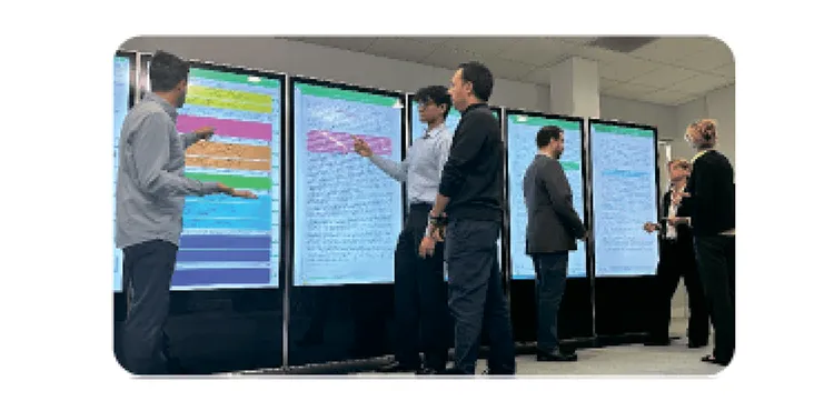Researchers working at a wall of large touchscreens in a collaboration room